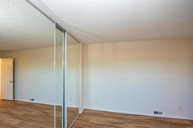 unfurnished bedroom with a textured ceiling and wood-type flooring