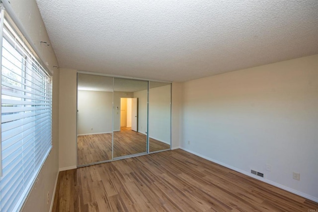 unfurnished bedroom featuring a textured ceiling, a closet, and hardwood / wood-style flooring