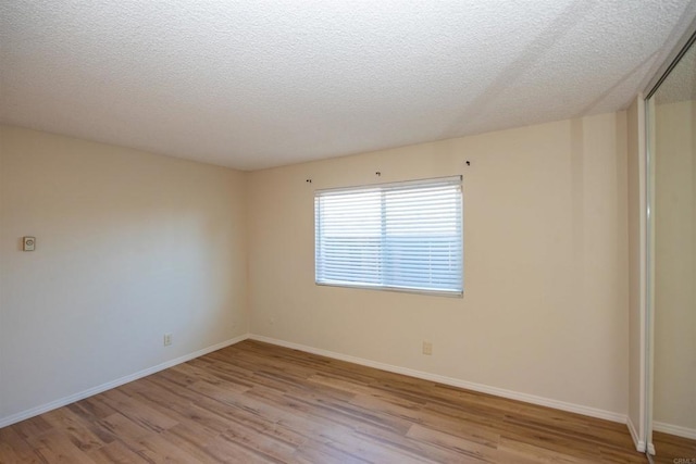 spare room featuring a textured ceiling and light wood-type flooring