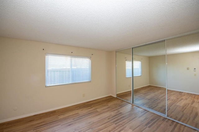 unfurnished bedroom with a textured ceiling, hardwood / wood-style floors, and a closet