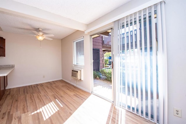 interior space featuring a wall unit AC, ceiling fan, and light hardwood / wood-style flooring