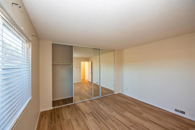 unfurnished bedroom featuring a textured ceiling, a closet, and light hardwood / wood-style floors