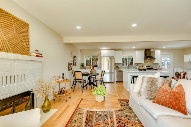 living room featuring separate washer and dryer, a brick fireplace, and light hardwood / wood-style floors