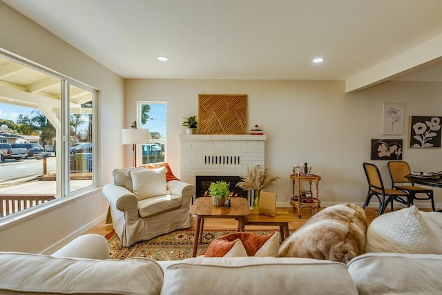 living room with a brick fireplace, a healthy amount of sunlight, and hardwood / wood-style floors