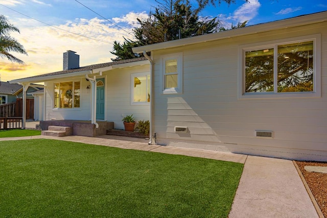 back house at dusk featuring a lawn