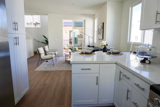 kitchen featuring white cabinets, hardwood / wood-style floors, kitchen peninsula, and a healthy amount of sunlight