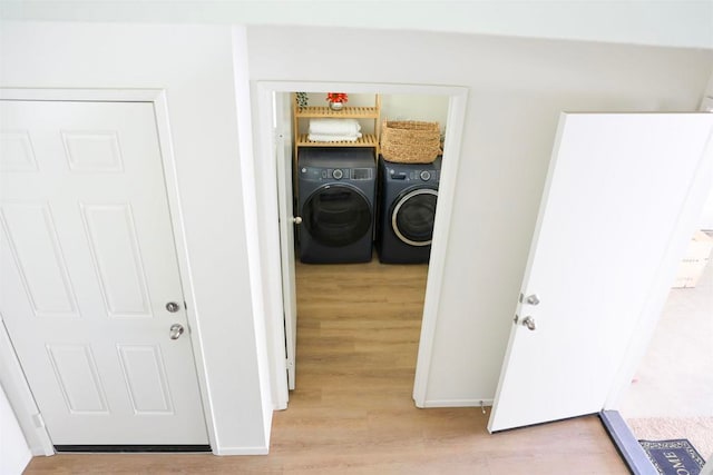 laundry area with separate washer and dryer and light hardwood / wood-style flooring