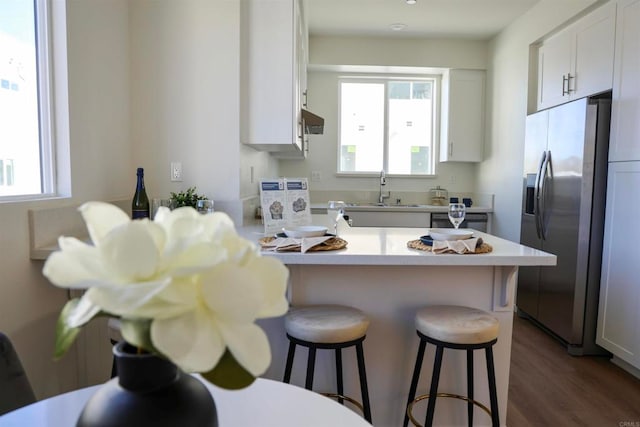 kitchen with appliances with stainless steel finishes, a breakfast bar, dark wood-type flooring, sink, and white cabinets