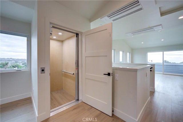 bathroom with hardwood / wood-style floors, elevator, and vaulted ceiling