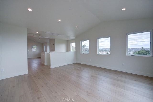 unfurnished room featuring a wealth of natural light, lofted ceiling, and light wood-type flooring