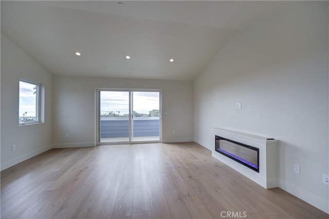 unfurnished living room with vaulted ceiling, light hardwood / wood-style flooring, and plenty of natural light