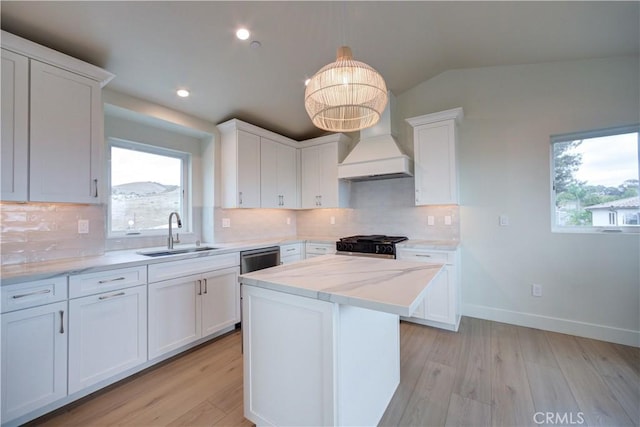 kitchen featuring white cabinetry, sink, a healthy amount of sunlight, and custom range hood