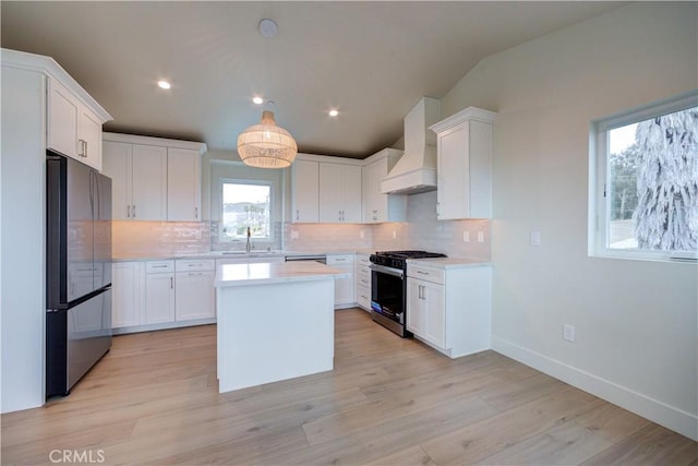 kitchen featuring premium range hood, white cabinets, sink, hanging light fixtures, and stainless steel appliances