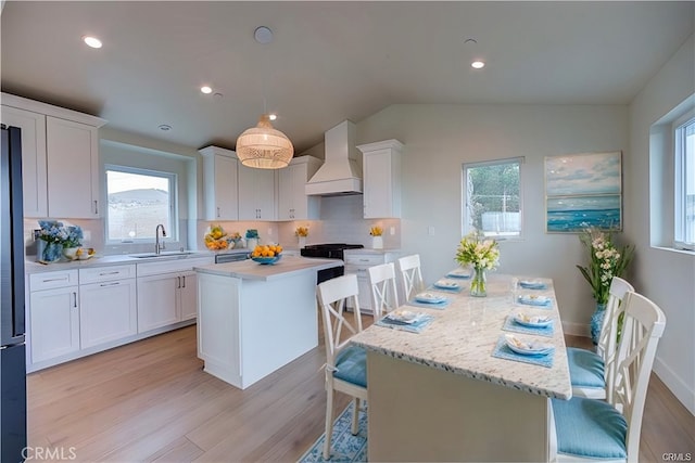 kitchen with a center island, backsplash, premium range hood, a kitchen breakfast bar, and sink