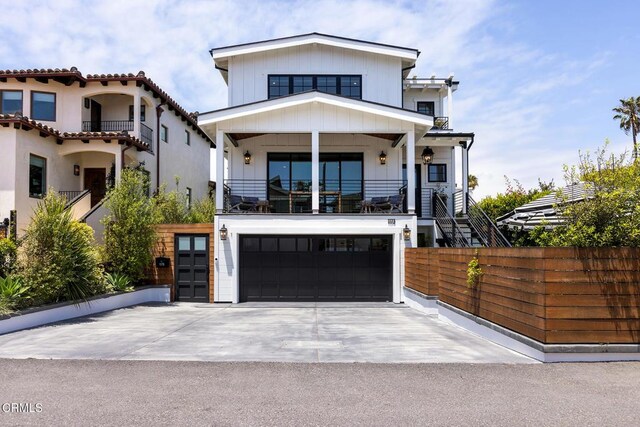 view of front facade with a garage, driveway, a balcony, stairway, and fence