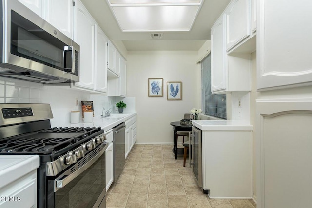 kitchen featuring backsplash, white cabinets, and stainless steel appliances