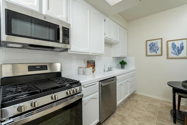 kitchen with appliances with stainless steel finishes, backsplash, sink, white cabinets, and light tile patterned flooring