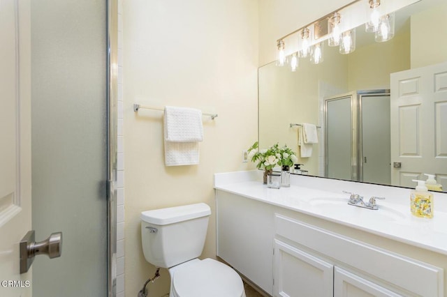 bathroom featuring vanity, a shower with door, and toilet