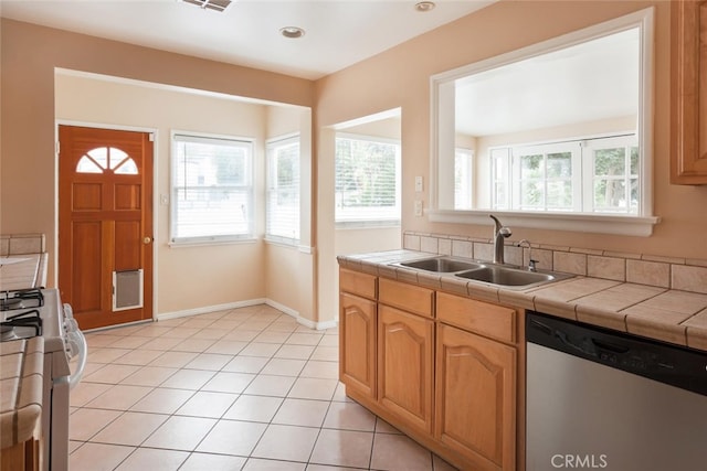 kitchen featuring sink, stainless steel dishwasher, tile countertops, stove, and light tile patterned flooring