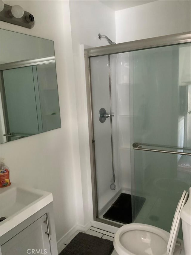 bathroom with a shower with door, vanity, and toilet