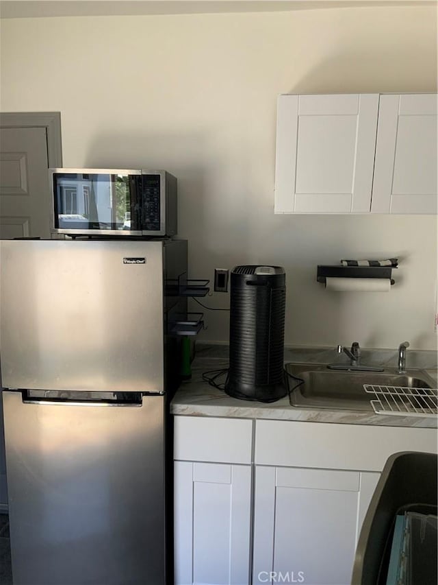 kitchen with stainless steel appliances, white cabinetry, and sink