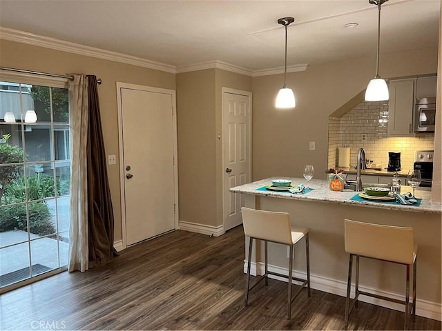 kitchen featuring stove, dark hardwood / wood-style floors, light stone countertops, decorative light fixtures, and a kitchen bar