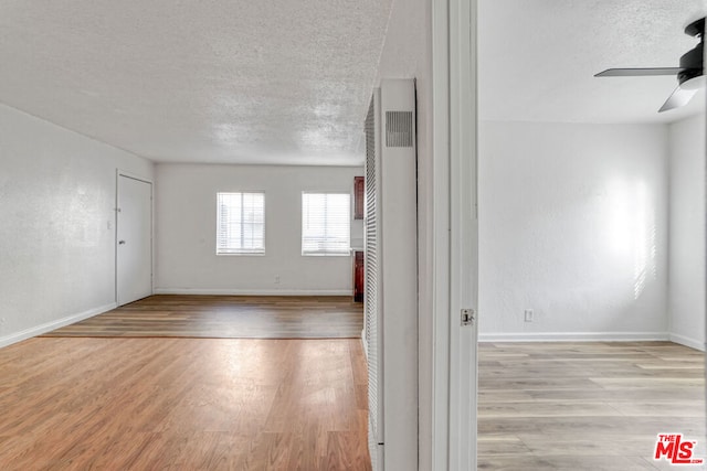 unfurnished room featuring light hardwood / wood-style floors, a textured ceiling, and ceiling fan