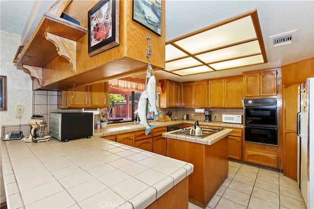 kitchen featuring a center island, stainless steel appliances, kitchen peninsula, tile countertops, and light tile patterned flooring