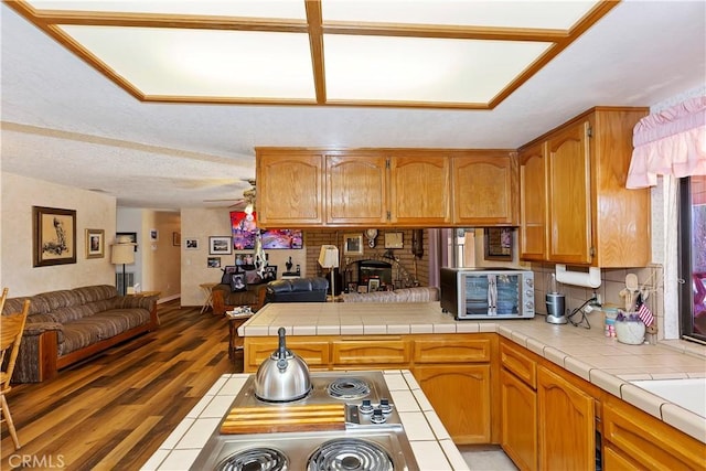 kitchen with a textured ceiling, dark hardwood / wood-style floors, tile counters, and ceiling fan