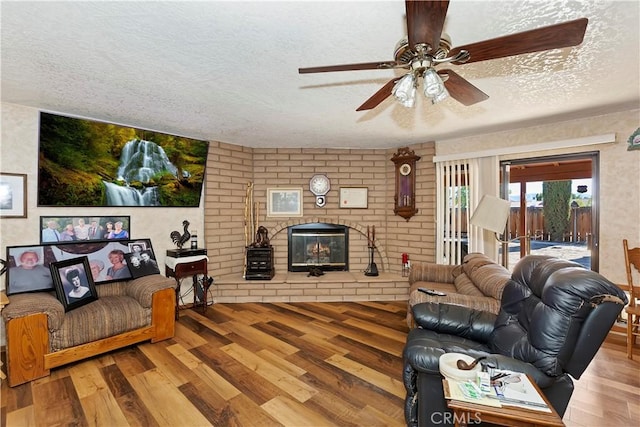 living room with a fireplace, ceiling fan, hardwood / wood-style floors, and a textured ceiling