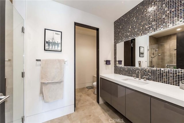 bathroom with decorative backsplash, vanity, toilet, and an enclosed shower