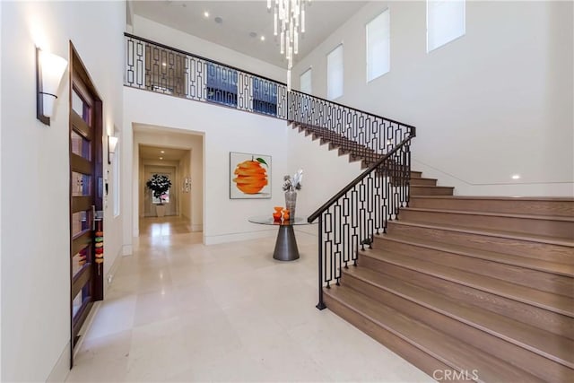 stairway featuring a towering ceiling and an inviting chandelier