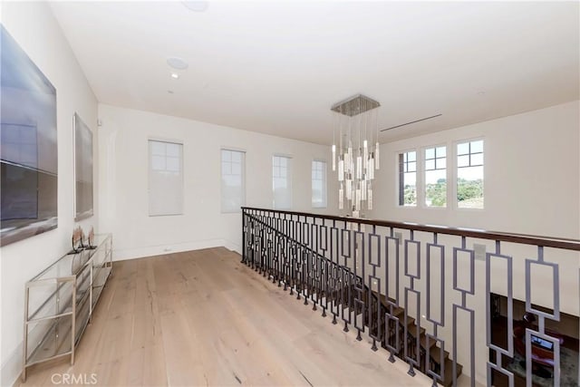 hall with light hardwood / wood-style floors and an inviting chandelier