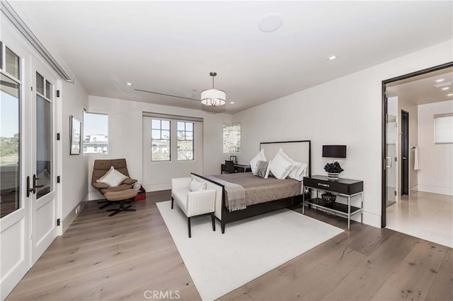 bedroom with light hardwood / wood-style flooring, french doors, and an inviting chandelier