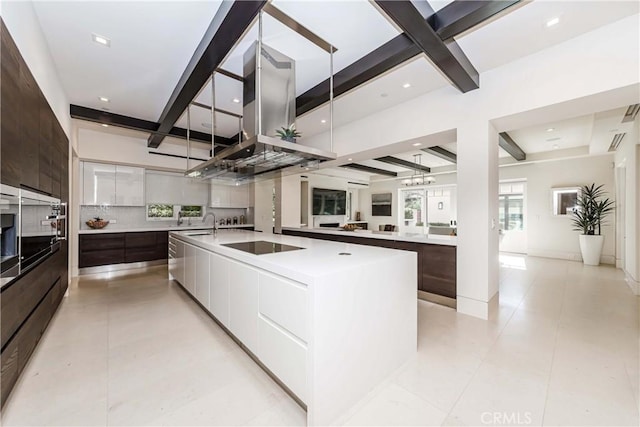 kitchen featuring black electric stovetop, dark brown cabinets, a center island with sink, white cabinetry, and oven