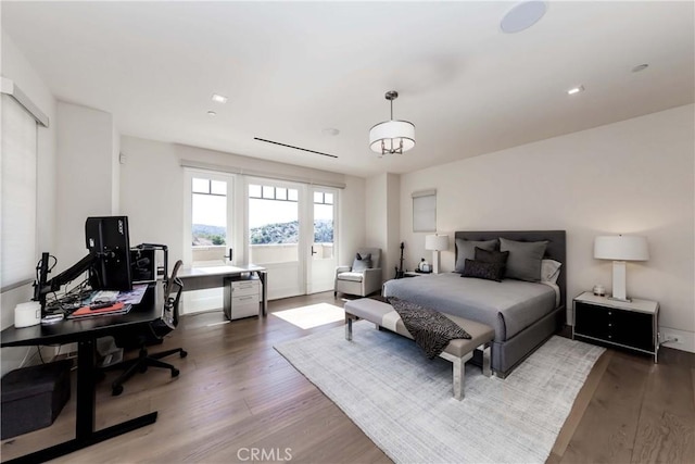 bedroom with wood-type flooring and an inviting chandelier