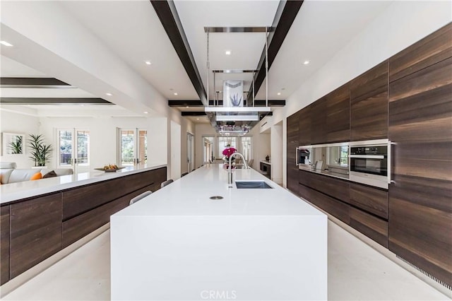 kitchen featuring stainless steel oven, a spacious island, sink, and french doors