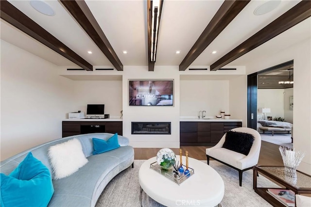 living room featuring beamed ceiling and light hardwood / wood-style floors