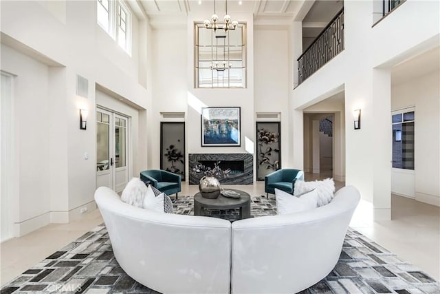 living room featuring a fireplace, a high ceiling, an inviting chandelier, and french doors