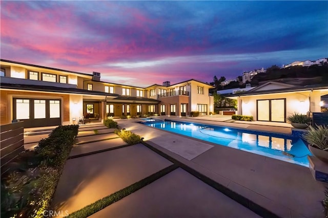 pool at dusk with a patio area