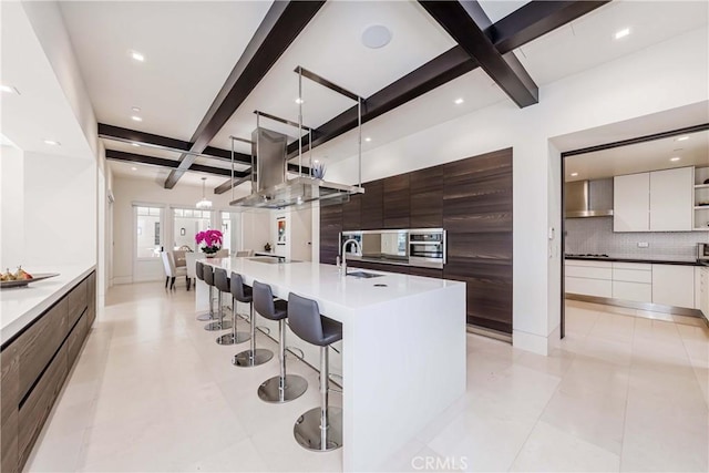 kitchen featuring white cabinetry, sink, stainless steel oven, tasteful backsplash, and a kitchen island with sink