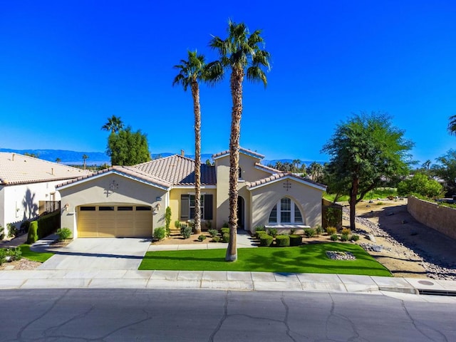 mediterranean / spanish-style home featuring a mountain view, a garage, and a front lawn