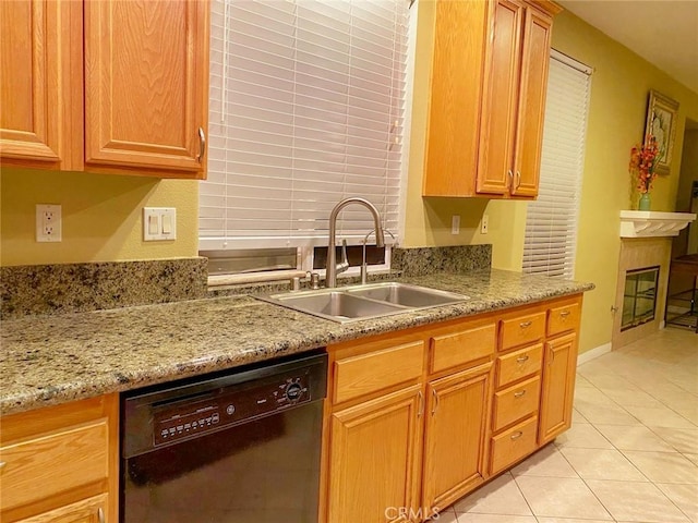 kitchen with light stone counters, sink, a tile fireplace, light tile patterned floors, and black dishwasher