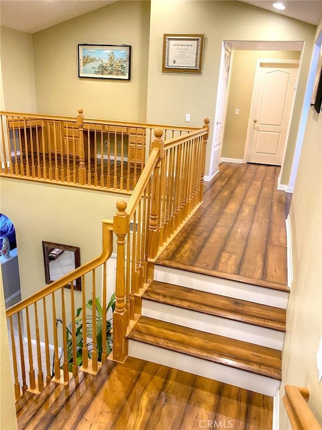 stairway featuring hardwood / wood-style flooring and vaulted ceiling