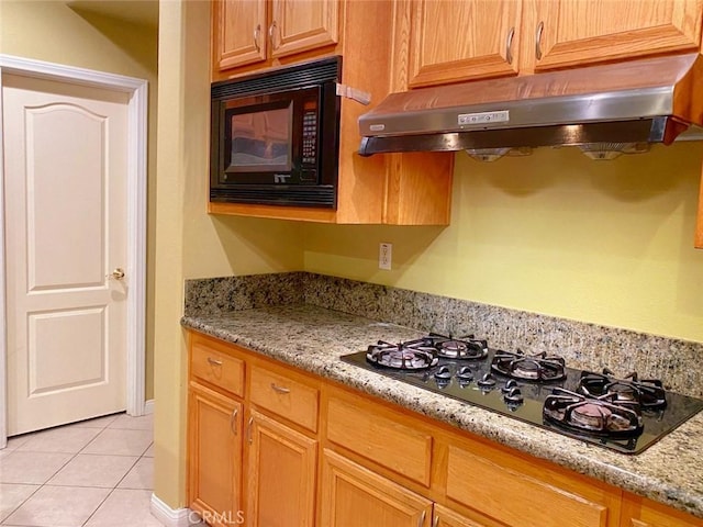 kitchen with light stone countertops, light tile patterned floors, and black appliances