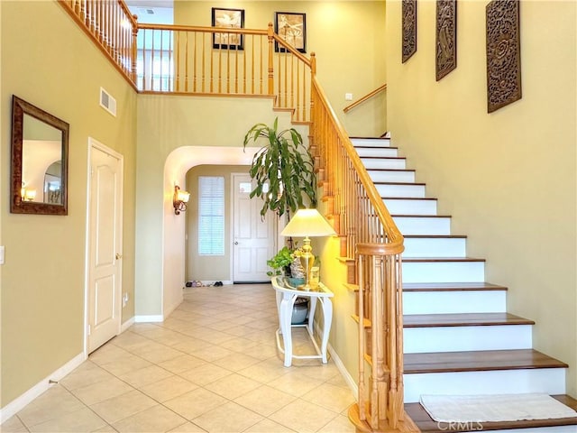 stairs with tile patterned floors and a towering ceiling