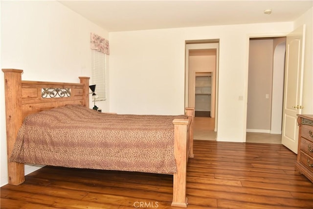 bedroom with a spacious closet and wood-type flooring