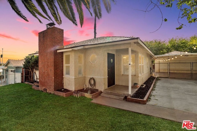 back house at dusk featuring a lawn