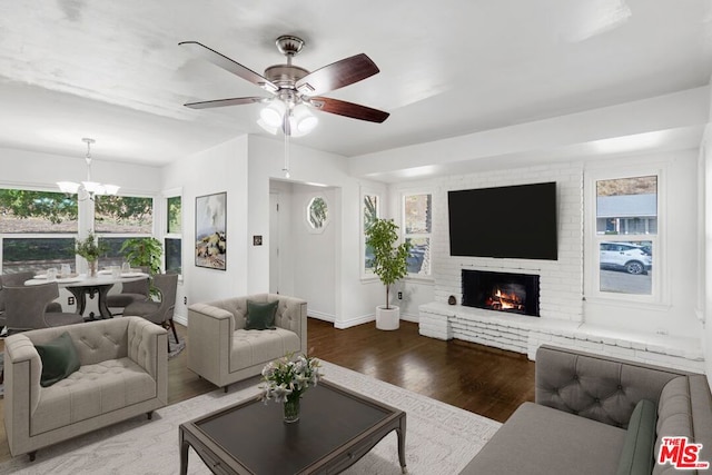 living room featuring ceiling fan with notable chandelier, a wealth of natural light, hardwood / wood-style floors, and a fireplace