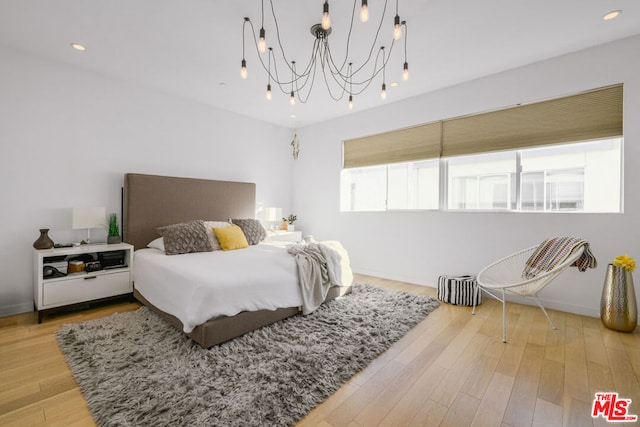 bedroom with hardwood / wood-style flooring and an inviting chandelier